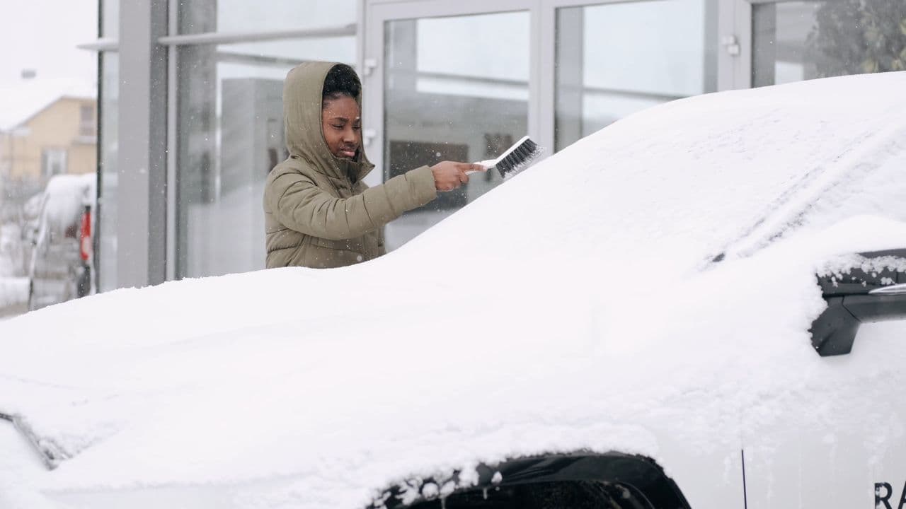 Une personne déneige une voiture